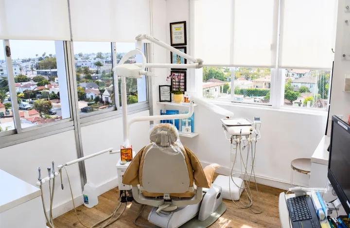 Treatment room with a cream dental chair and a window view over Beverly Hills