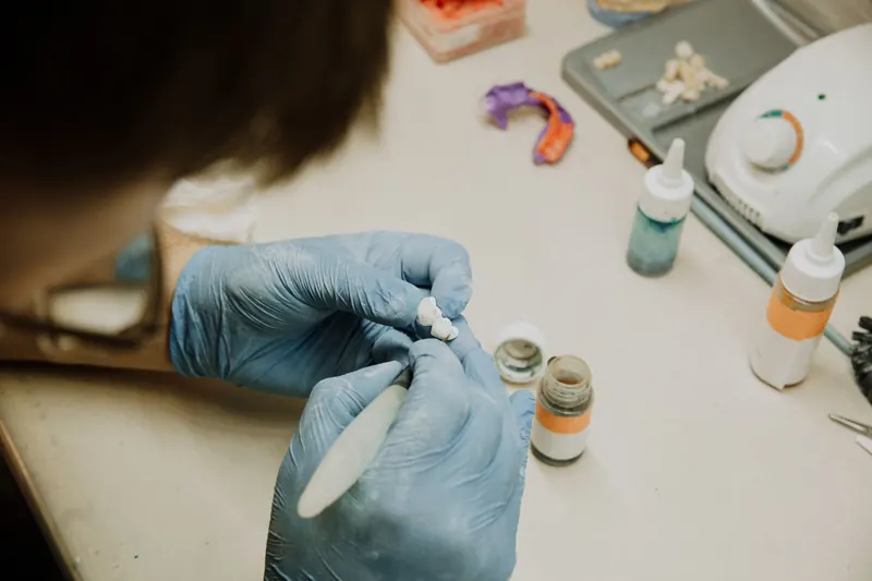 A dental technician refining a ceramic crown in a lab